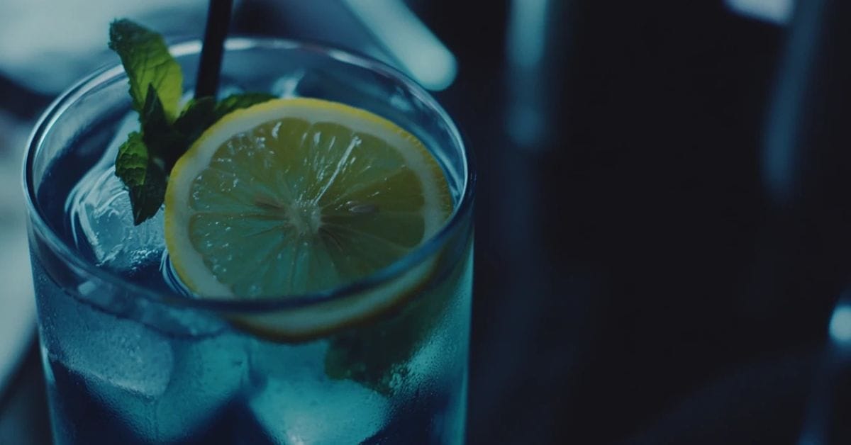 A refreshing glass of blue lemonade with lemon slices and mint