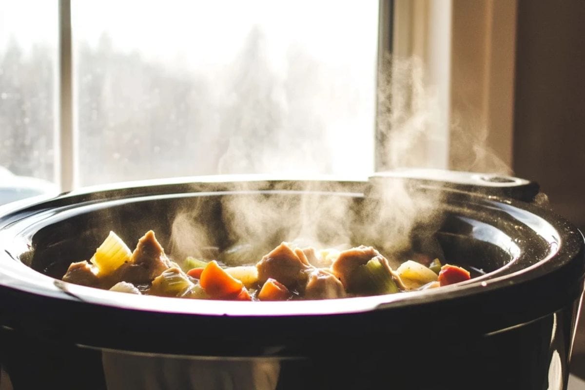 Frozen chicken cooking in a crockpot with vegetables