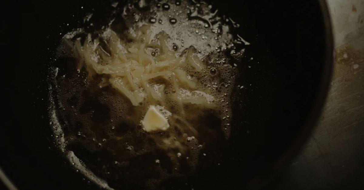 Hash browns frying in a pan with butter and oil.