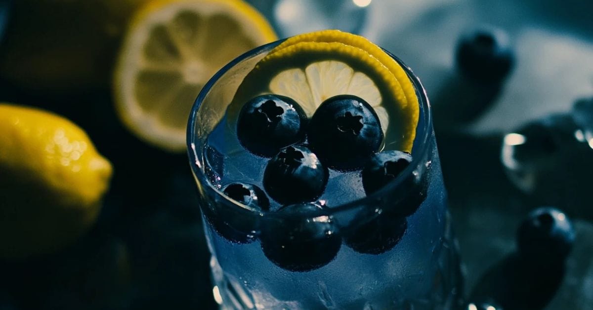 glass of blue lemonade with lemon slices and blueberries