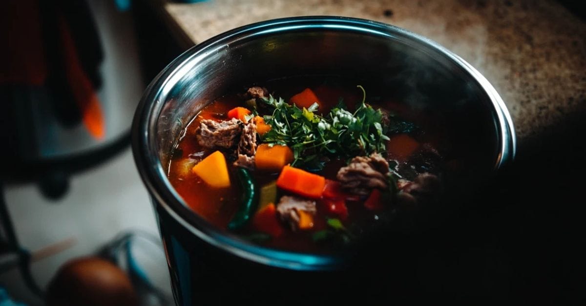 Crockpot filled with vegetables and meat cooking slowly