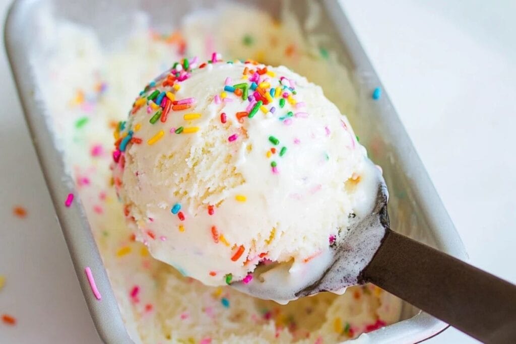 A scoop of birthday cake ice cream topped with colorful sprinkles