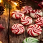 A plate of homemade peppermint candy with red and white swirls, placed on a holiday-themed table.