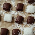 A batch of coconut candy, some chocolate-coated, arranged neatly on parchment paper.