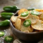 A bowl of crispy jalapeño chips with fresh jalapeño slices.