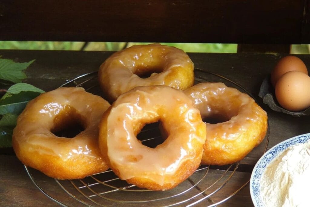 A batch of golden Amish doughnuts glazed and cooling on a rack.