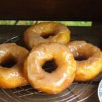 A batch of golden Amish doughnuts glazed and cooling on a rack.