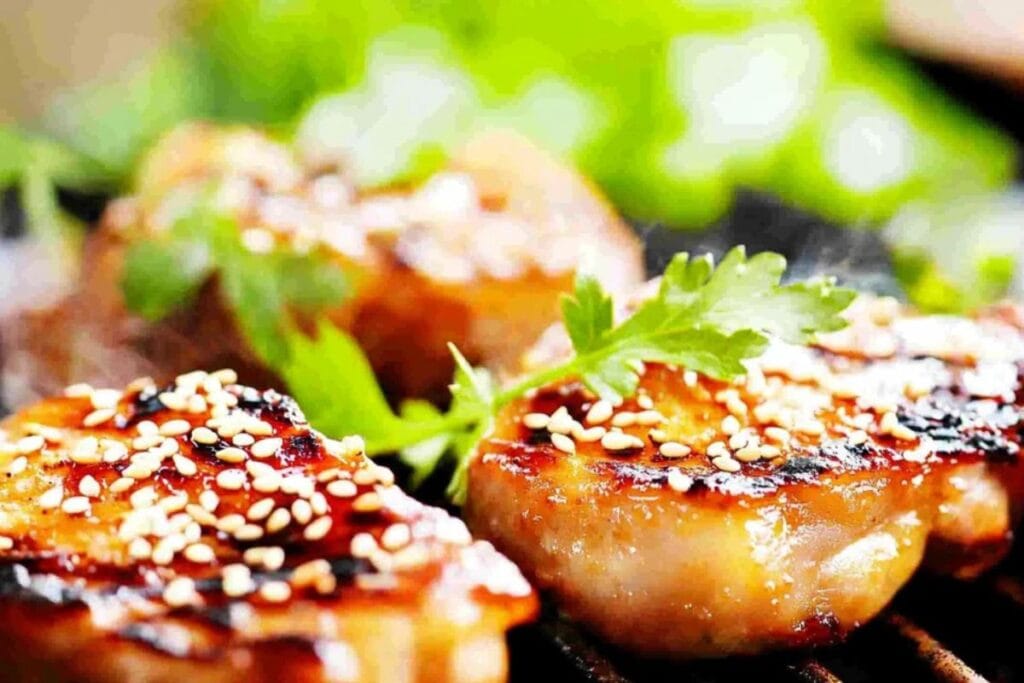 Juicy teriyaki chicken thighs with grill marks, garnished with sesame seeds and green onions.