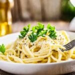 A bowl of creamy vegetarian spaghetti carbonara topped with fresh parsley and black pepper.