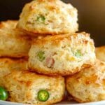 Fluffy ham and jalapeño biscuits on a rustic wooden board, golden brown and freshly baked.